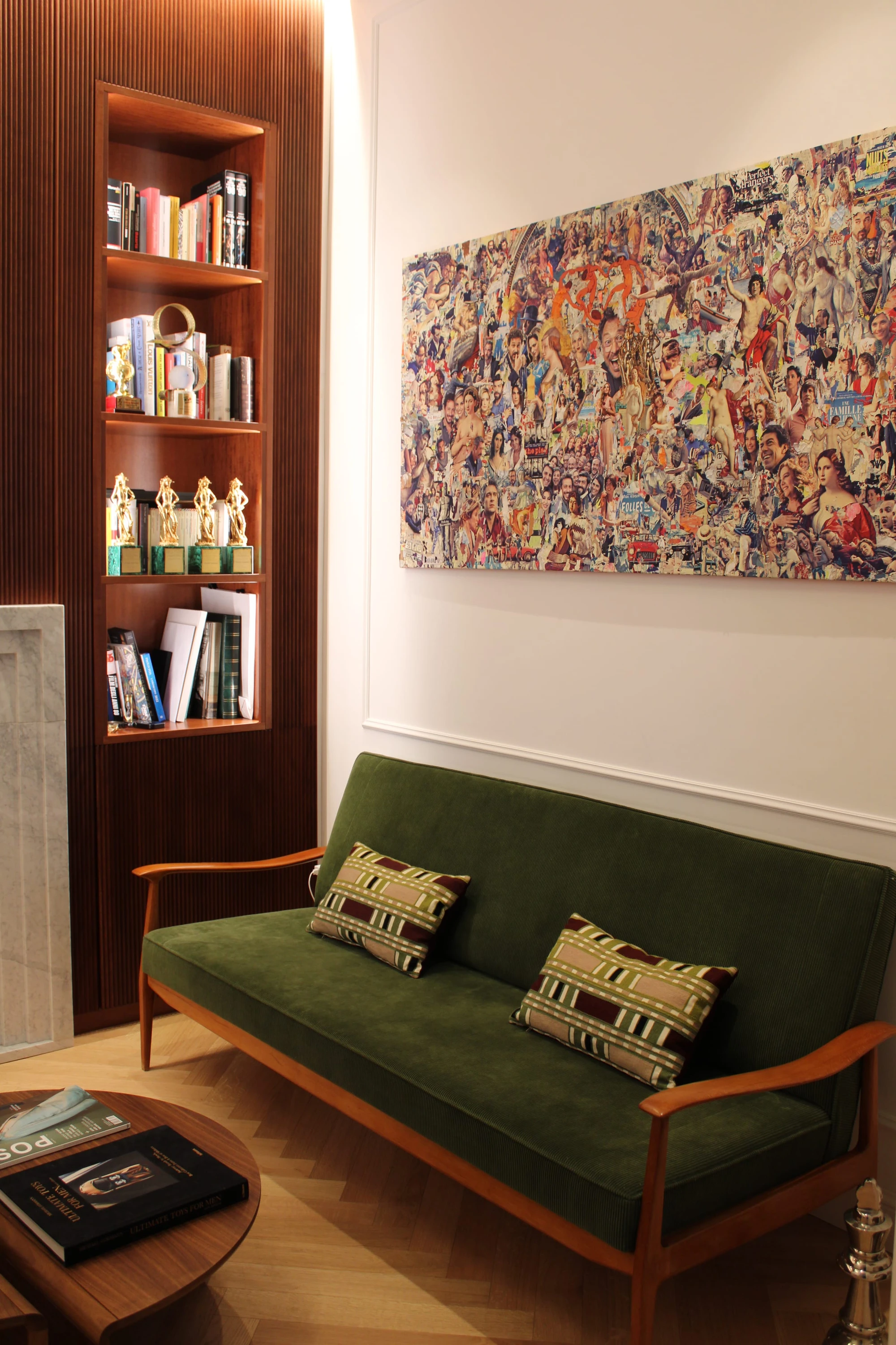 Salotto BM Apartment Belardi: divanetto vintage in velluto verde a coste con struttura in legno chiaro e cuscini geometrici, libreria a colonna in legno e collage artistico sopra al divano